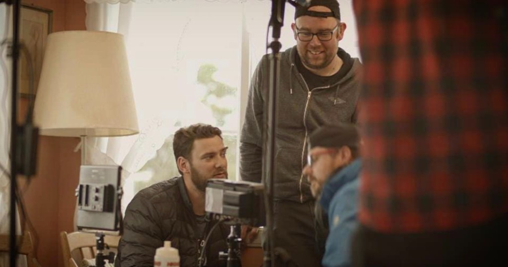 James Ian Gray with crew on set, reviewing a production monitor